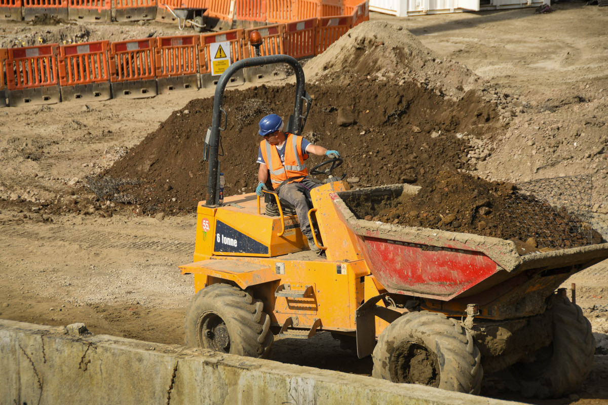Image shows construction worker on site in construction vehicle.