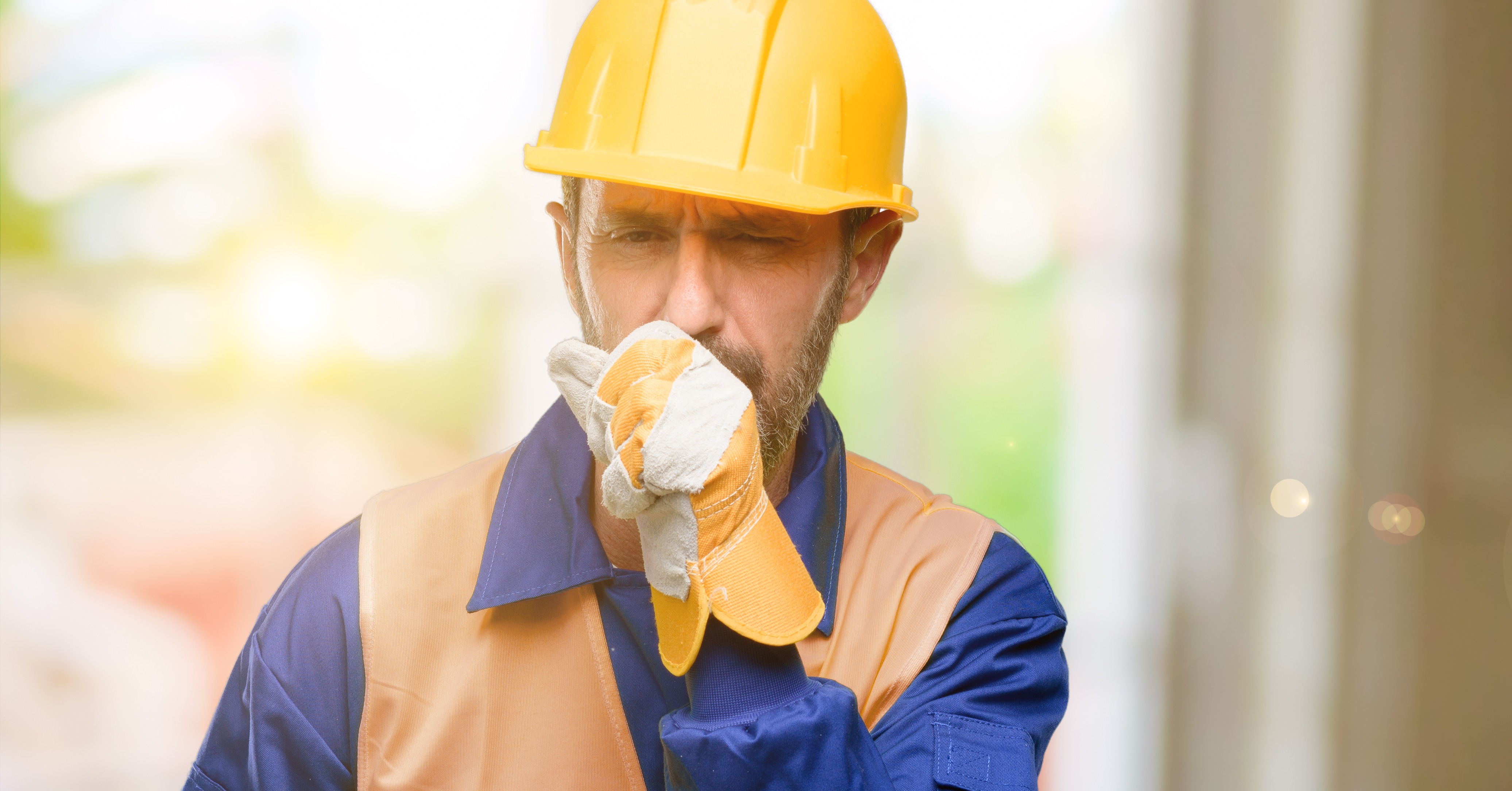image shows a construction worker coughing