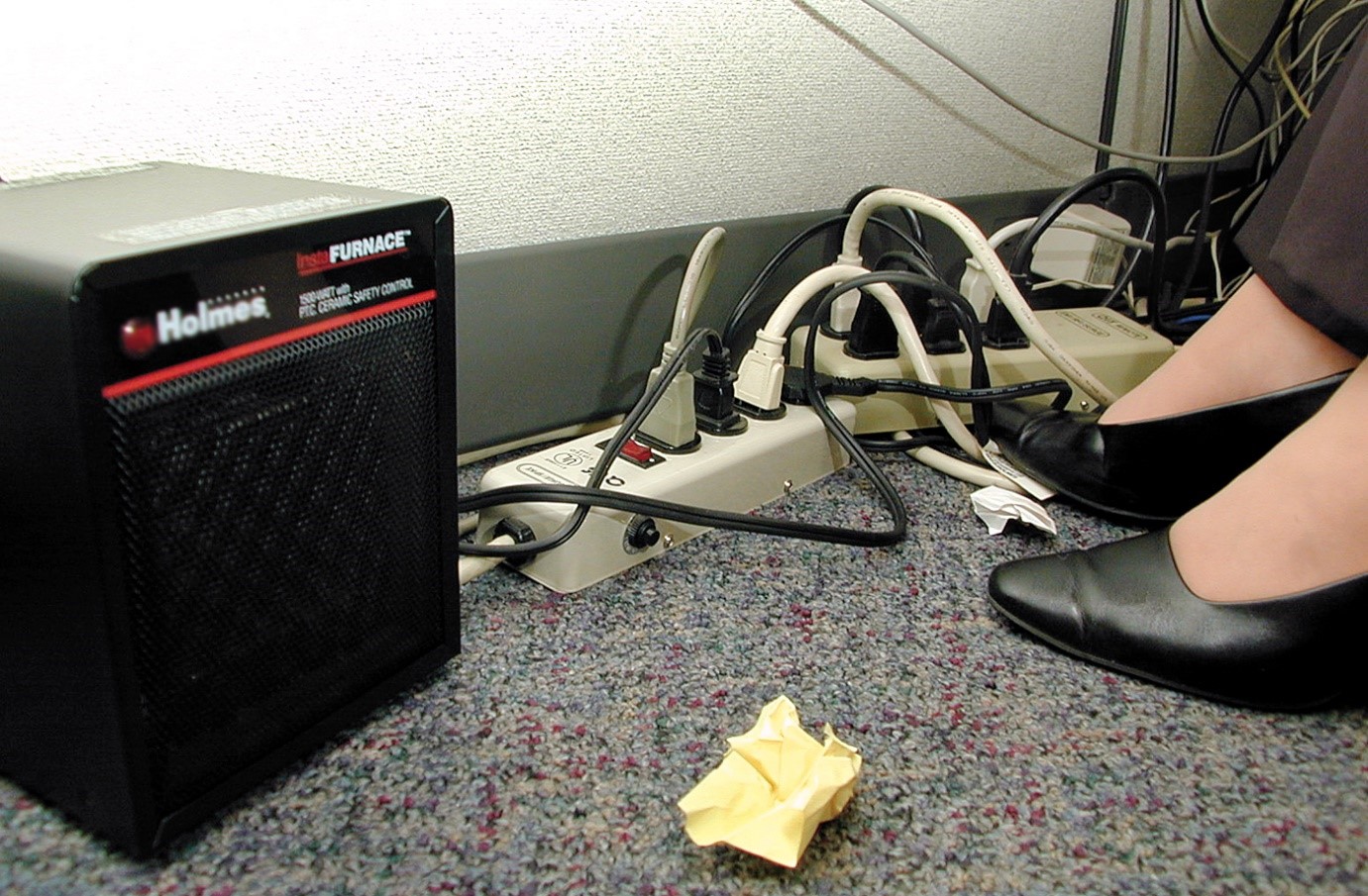 Image shows overloaded plug sockets in office.