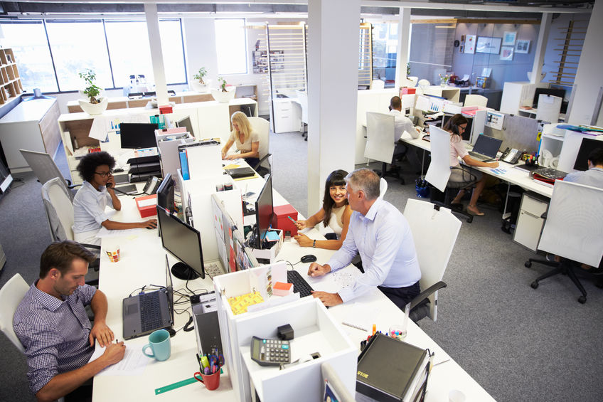 image shows an office full of employees taking care to be safe in the workplace 